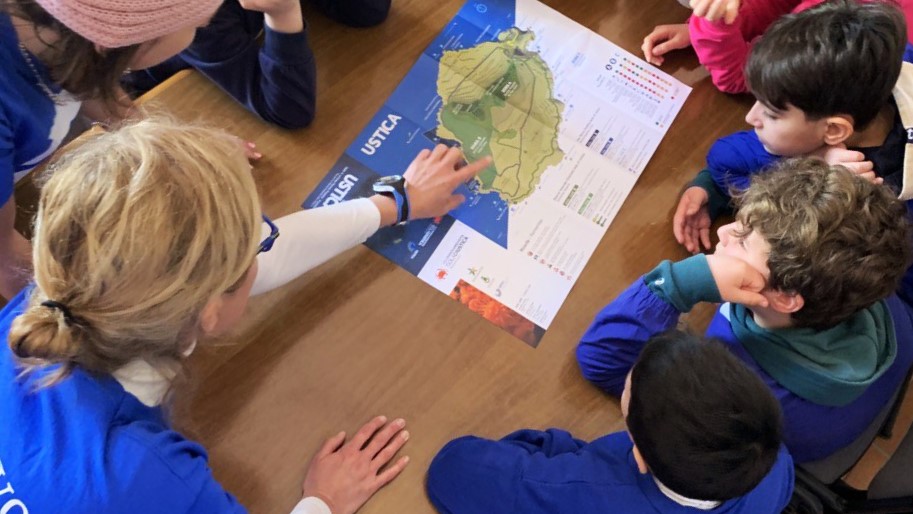 Educatori ambientali di Marevivo che mostrano la mappa dell'AMP di Ustica ai bambini del programma Delfini Guardiani